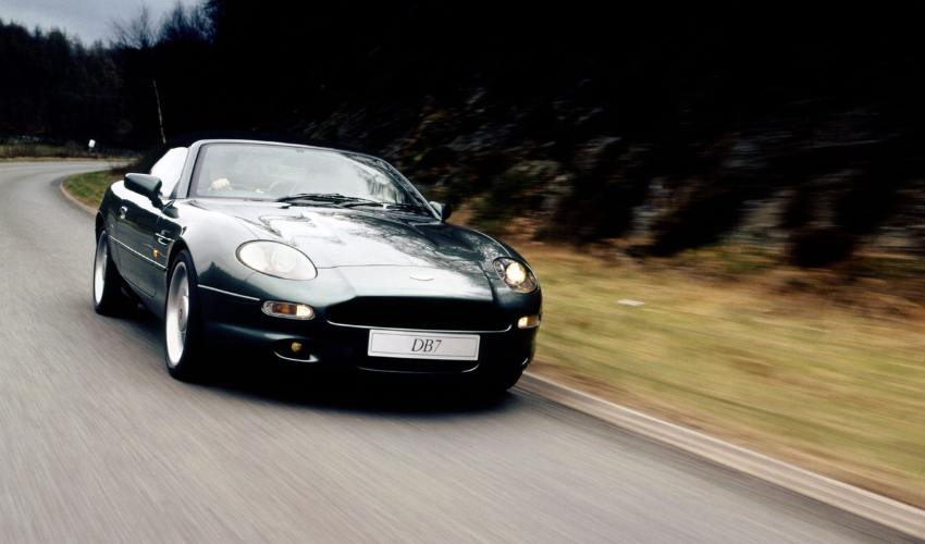 Grey Aston Martin DB7 driving along a road