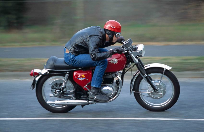 Man riding a red and silver motorbike at speed