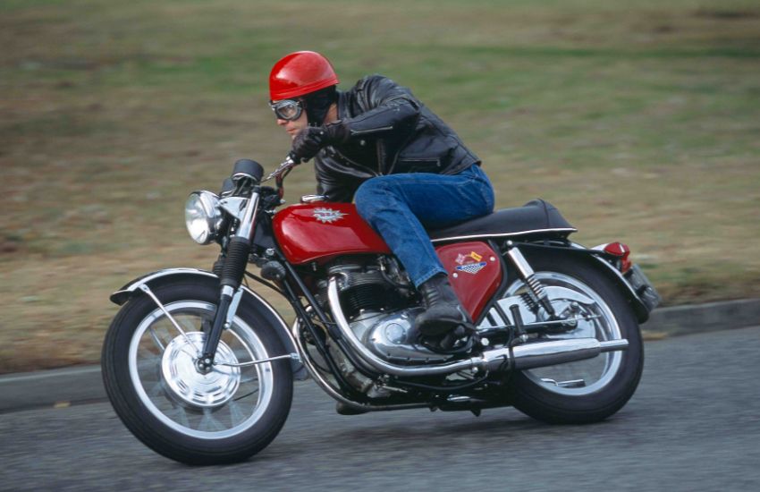 Man riding a motorbike around a left leaning bend in the road