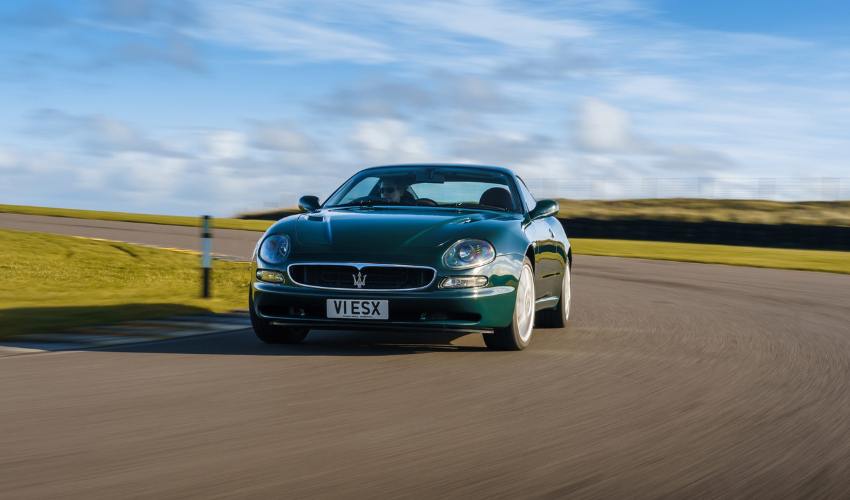 Green Maserati 3200 GT being driven round a corner on a race track