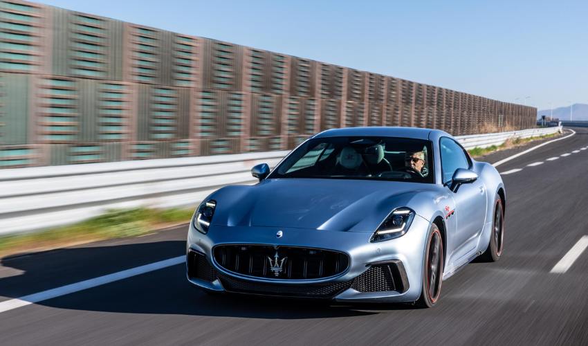 Metallic blue Maserati GranTurismo driving along a road