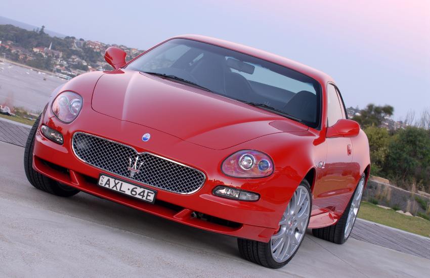 Front view of a red Maserati Gransport parked up with a lake in the background