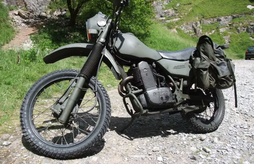 Green motorbike parked up with green grassy verge in the background