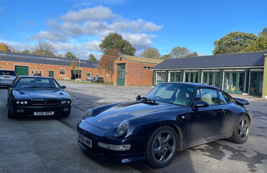 Two cars packed in a car park with buildings in the background