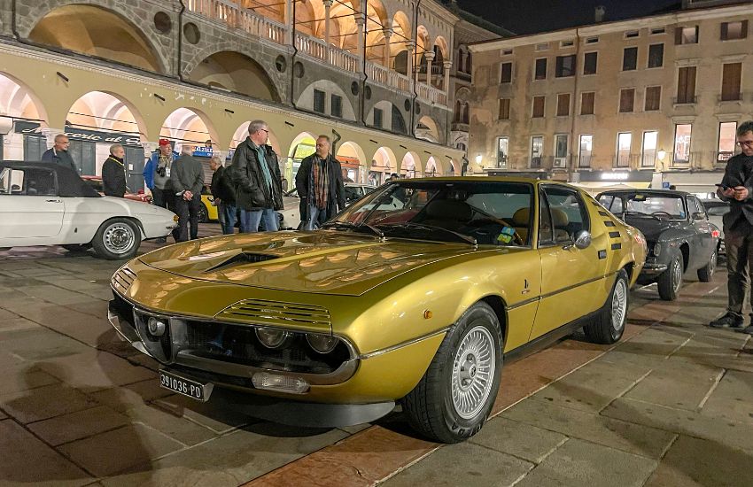 Gold Alfa Romeo Montreal sports coupe parked on a busy street