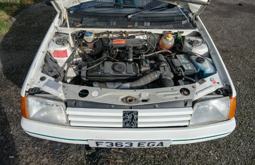 Bonnet open of a white classic car exposing engine bay