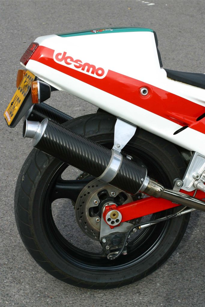 Rear wheel and exhaust of a red, which and green motorbike