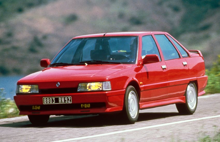 Red classic car driving along a road at speed