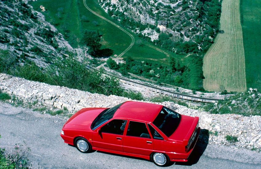 Top down view of a red Renault 21 parked on a cliff edge overlooking fields