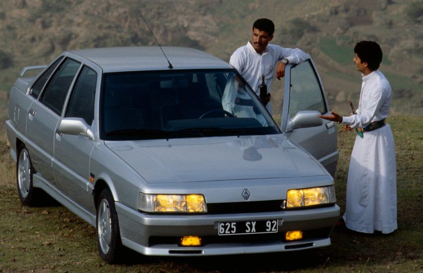 Two men standing alongside a silver parked car