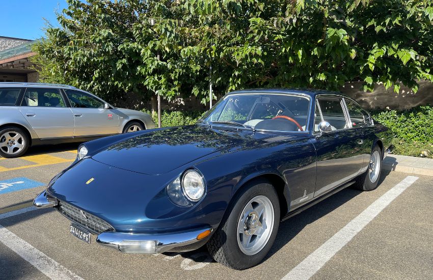 Blue Ferrari 365 GT 2+2 grand tourer parked in front of bushes