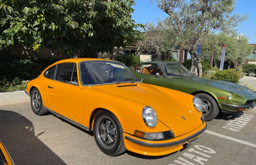 First-generation Porsche 911 (F-body) in Signal Orange paint, parked alongside a first-generation Nissan Z-c