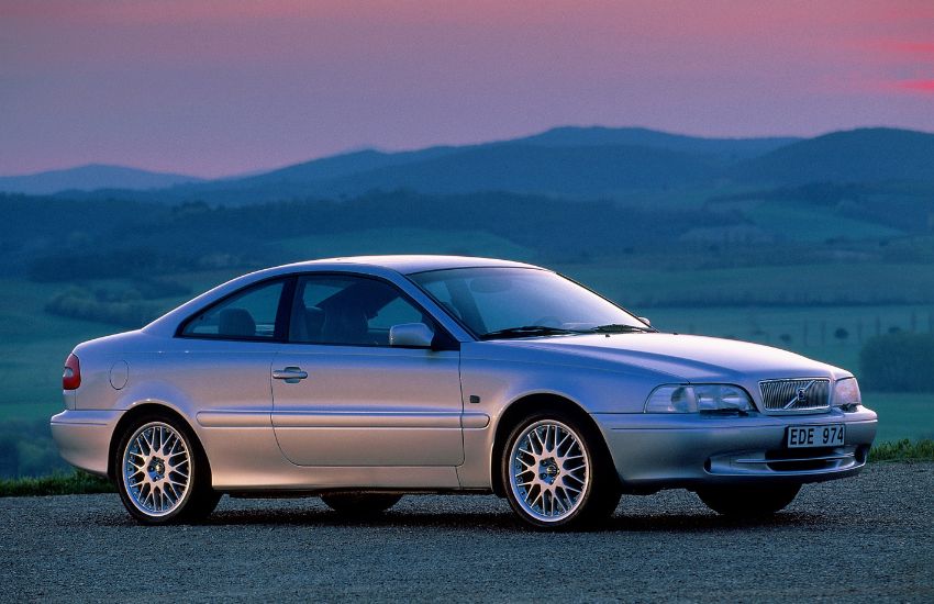 Side view of a silver Volvo C70 parked on a hill during sunset