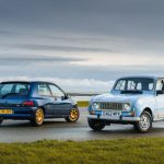 Two classic cars parked on a beach front