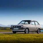 Beige Ford Fiesta parked with mountains and coastline in te background