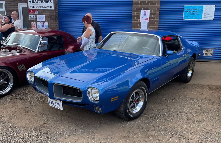Blue Pontiac Firebird American Muscle car parked in front of a building