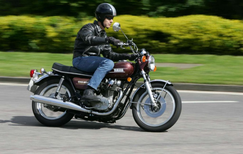 Man riding a metallic brown classic Yamaha motorbike