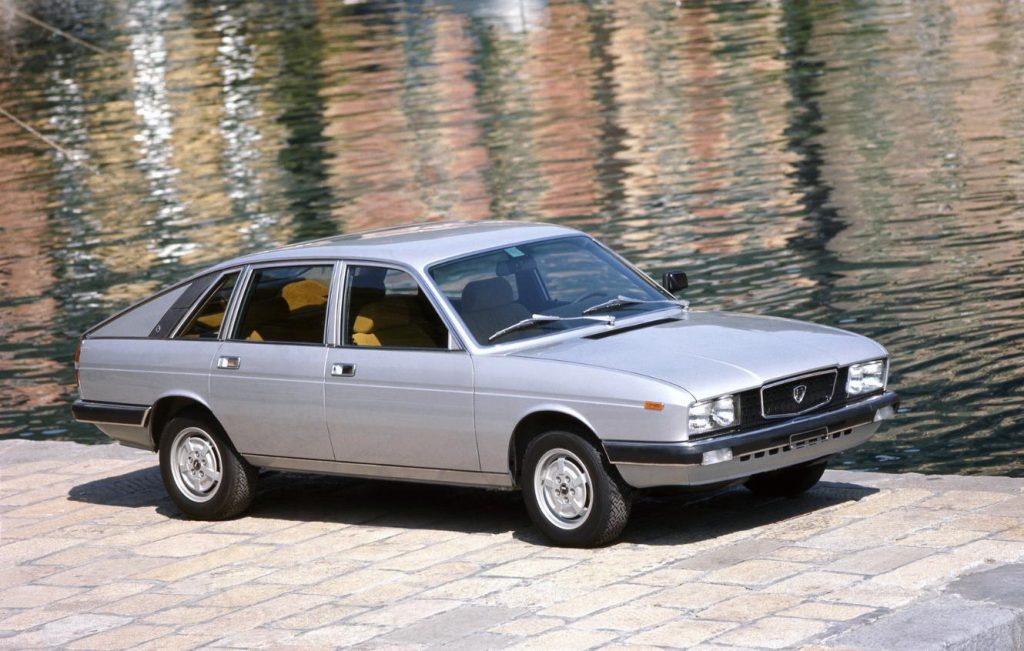 Silver classic car parked in front of a lake