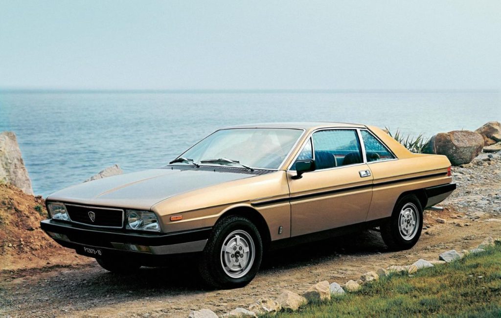 Side view of a gold Lancia Gamma parked on sea front