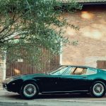 Green Maserati Ghibli parked on a street in front of a brick building