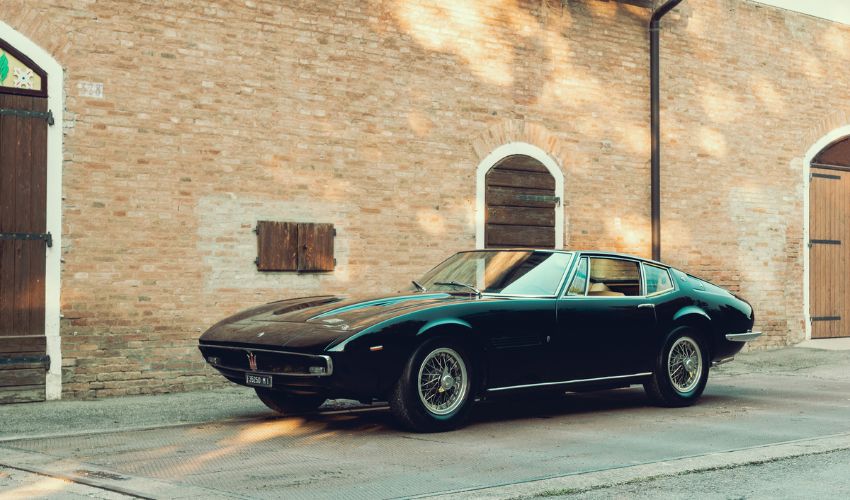 Green Maserati Ghibli parked on a street in front of a brick building