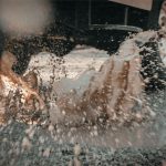 Car driving through pot hole filled with water