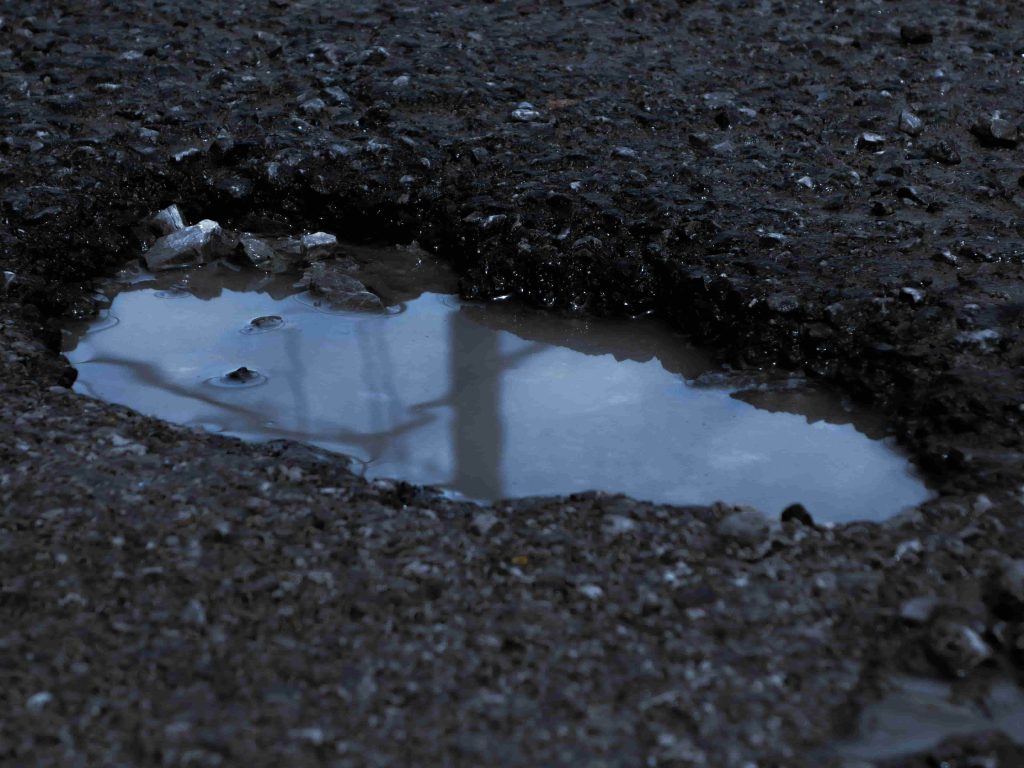 UK pot hole on a tarmac road filled with water