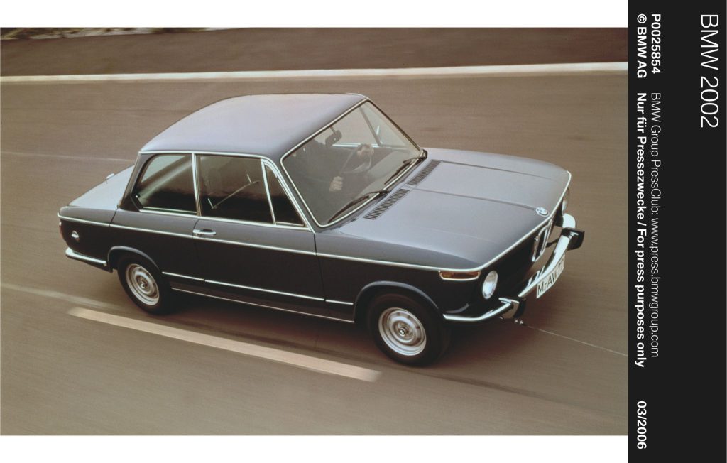 Blue BMW 02 Series being driving along a road