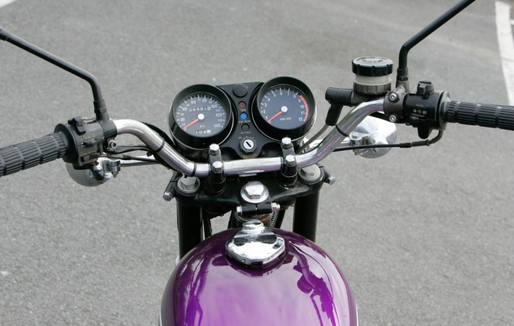 Rider's view of a motorcycle, including the handlebars, instrument cluster, and the top of the fuel tank