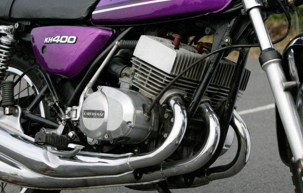 Engine and exhaust system of a Kawasaki KH400 motorcycle, along with a portion of the frame and rear wheel.