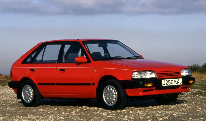 Side view of a red Sao Penza parked on a gravel surface