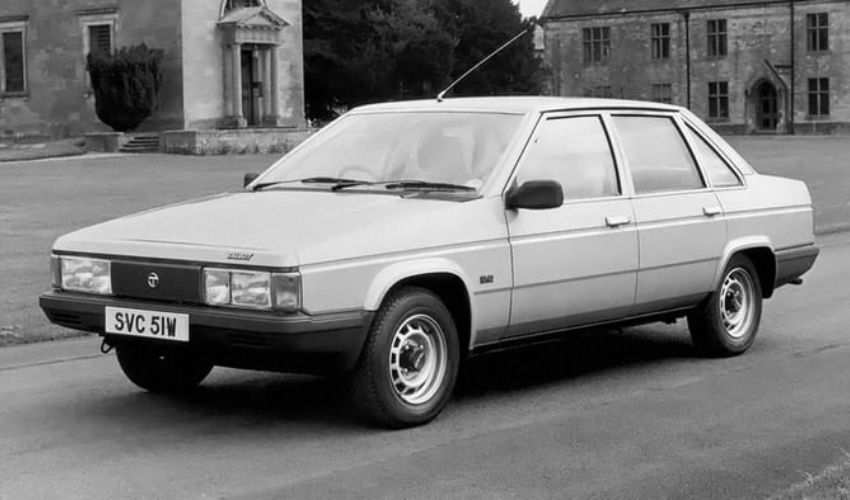 Greyscale of a Tagora 2.2 parked in front of a lawn and buildings
