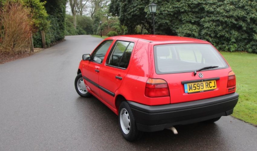Rear view of a red Volkswagen Golf MK3 parked on a road