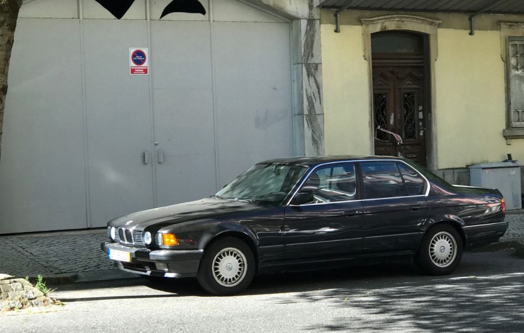 A black BMW E32 7 Series sedan parked on a street