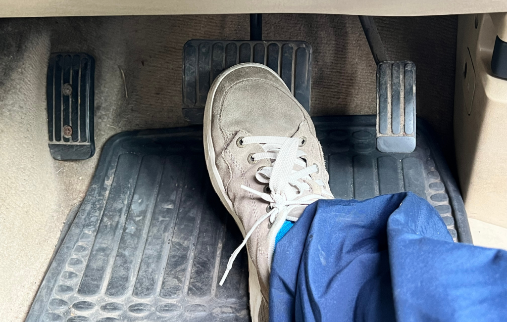 Right foot placed on the brake pedal of a car