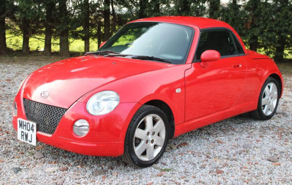 Red Daihatsu Copen parked up on gravel drive