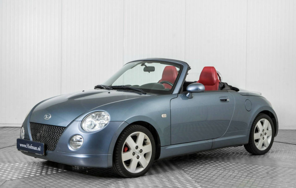 Parked metallic blue convertible Daihatsu Copen with the roof down