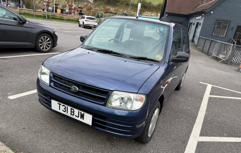 Dark metallic blue Daihatsu Cuore parked in a car park