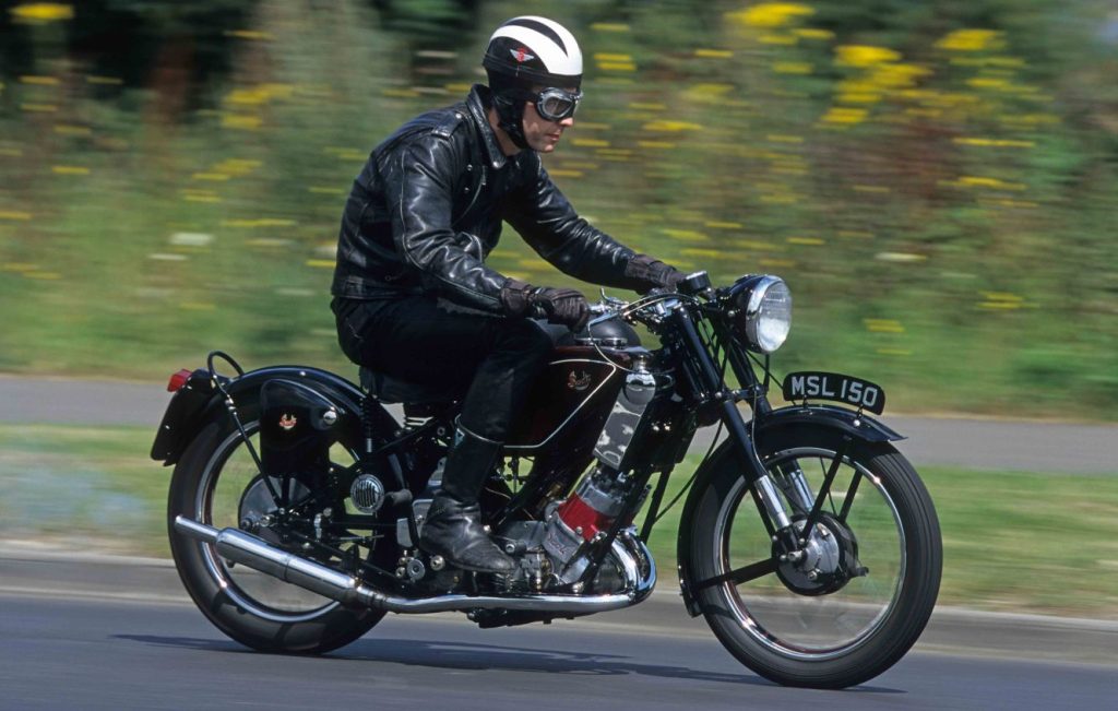 Man riding a Scott Flying Squirrel along a road at speed