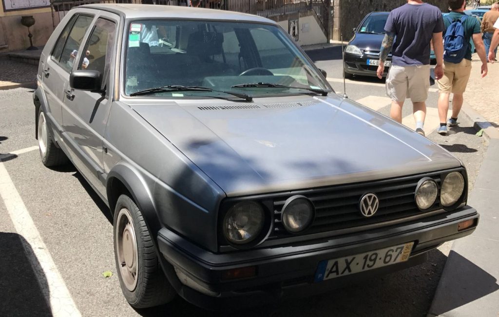 A classic silver Volkswagen Golf Mk2 parked on a cobblestone street