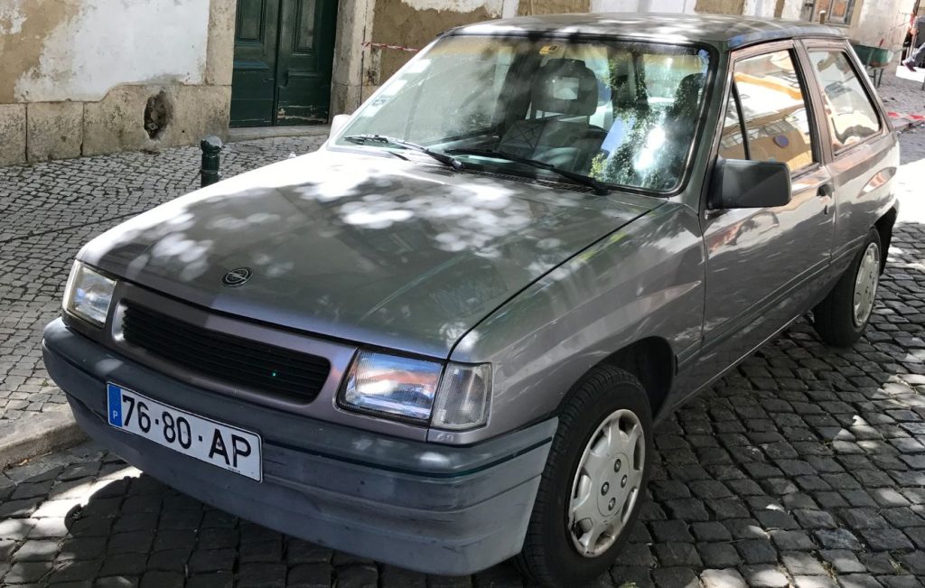 A grey Opel Corsa A parked on a cobbled street