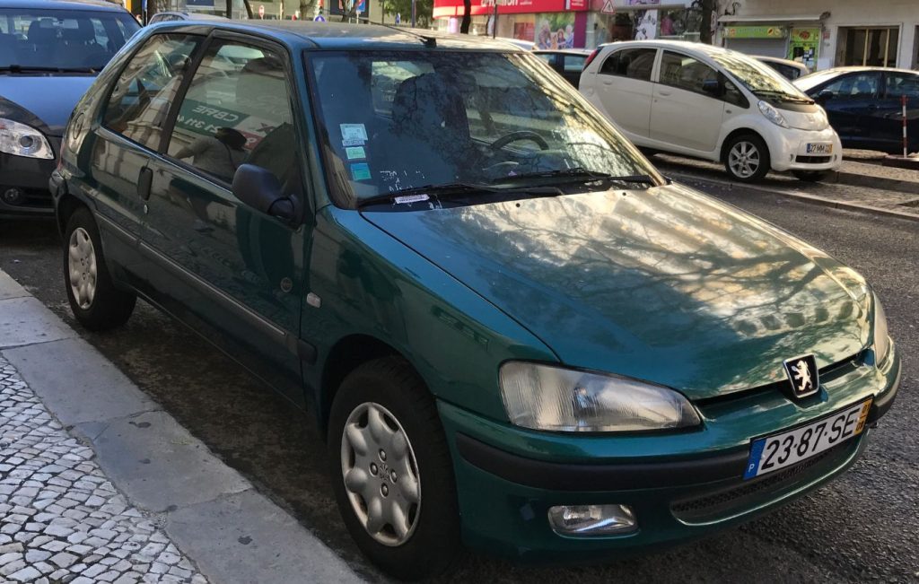 A green Peugeot 106 hatchback parked on a cobbled street
