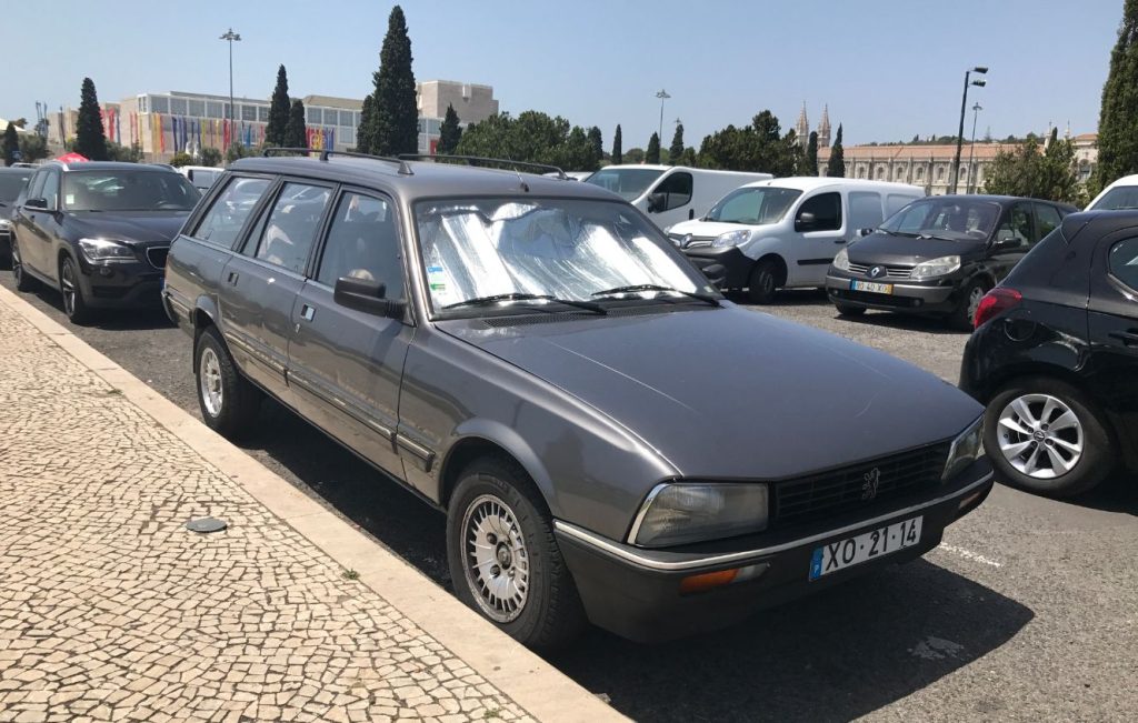 Dark metallic grey Peugeot 505 Estate parked on a busy street