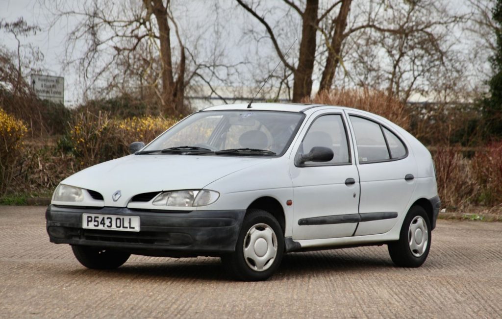 Front side view of a white Renault Megane parked in front of bushes