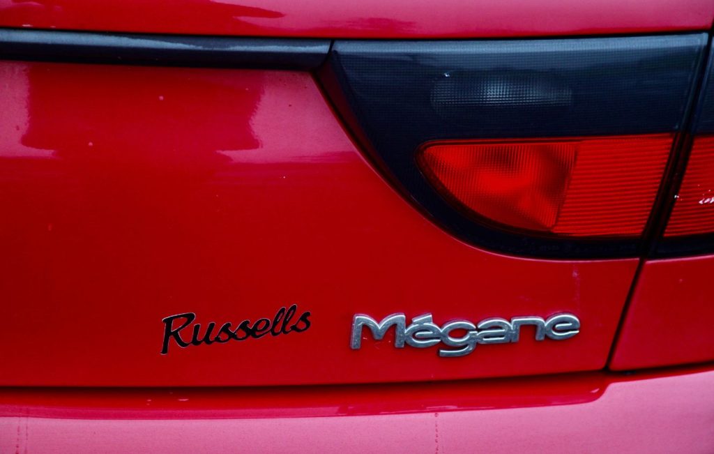 Rear boot and light of a red Renault Mégane I Coupe featuring a custom "Russells" badge