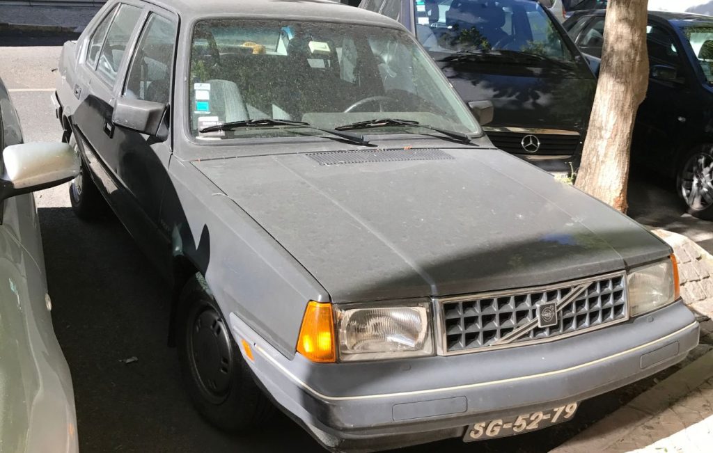 A dust-covered Volvo 340 parked on a city street