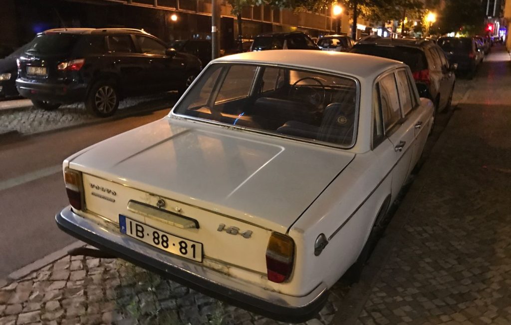 White Volvo 164 classic car parked on a city street at night