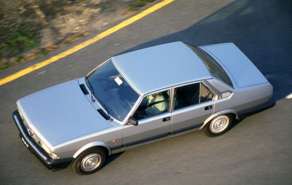 Top down view of a silver Alfa Romeo classic car driving along a road