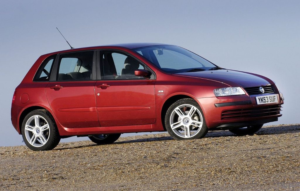 Metallic red Fiat Stilo parked on a gravelsurface