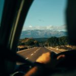 Man driving a car with sunlit mountains in thedistance